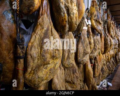 Cosce secche di maiale appendono sul mercato della carne. Piatto nazionale spagnolo di prosciutto o jamon in un negozio di alimentari. Shopping di maiale iberico nel supermercato Spagna. Asciutto e CUR Foto Stock