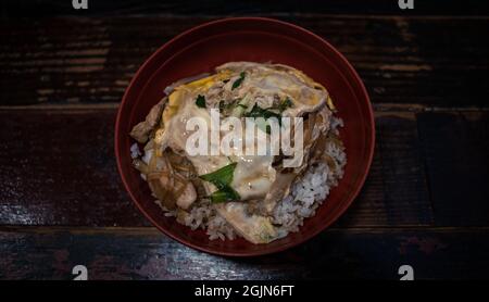 Oyakodon giapponese vista orizzontale dall'alto. Antipasto ciotola di riso con pollo e uova sul tavolo in legno del ristorante. Healt delizioso Foto Stock