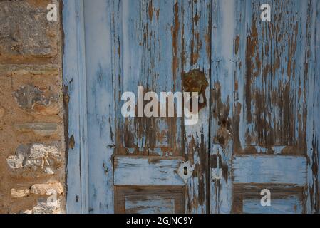 Vecchia casa rurale intemperiato chiaro blu porta di ingresso in legno con un antico schiaffo ottone su un muro di pietra a Galaxidi, Phocis Grecia. Foto Stock