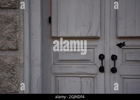 Vecchia casa neoclassica porta grigia in legno con un antico scheletro in ferro forgiato chiave e maniglia porta su una parete in pietra a Galaxidi, Phocis Grecia. Foto Stock