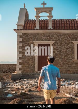 Vista posteriore di un giovane maschio che cammina verso la chiesa Foto Stock