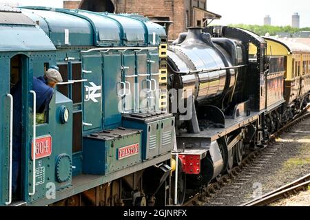 Didcot, Oxfordshire, Inghilterra - Giugno 2021: Il conducente guarda dalla cabina di una locomotiva diesel shunter mentre spinge un vecchio motore a vapore in un sidding Foto Stock