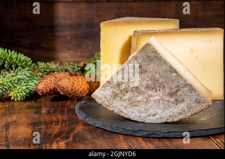 Collezione di formaggi, formaggi francesi di mucca comte, beaufort, abondance, tomo de savoie e coni di abete Foto Stock