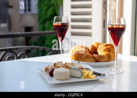 Bere del Kir Royal, aperitivo francese a base di creme de cassis con champagne, tipicamente servito in calici di flauto, con vista sul vecchio Foto Stock