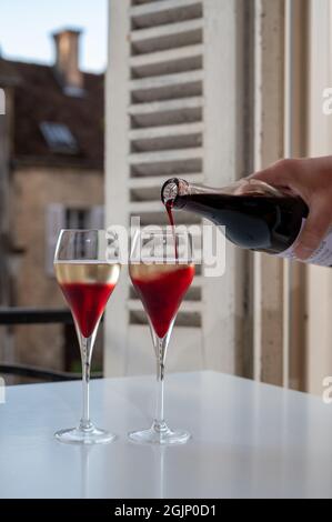 Bere del Kir Royal, aperitivo francese a base di creme de cassis con champagne, tipicamente servito in calici di flauto, con vista sul vecchio Foto Stock