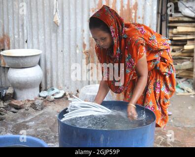 Non esclusiva: CITTÀ DI DHAKA, BANGLADESH, 9 SETTEMBRE: I lavoratori hanno battuto l'acqua di stoffa lungo un fiume inquinato. I lavoratori lavano, squillano fuori e asciugano il panno alon Foto Stock