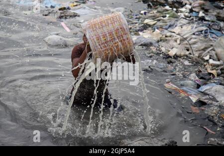 Non esclusiva: CITTÀ DI DHAKA, BANGLADESH, SETTEMBRE 09: I lavoratori hanno battuto l'acqua di stoffa lungo un fiume inquinato. I lavoratori lavano, squillano fuori e asciugano il panno alo Foto Stock