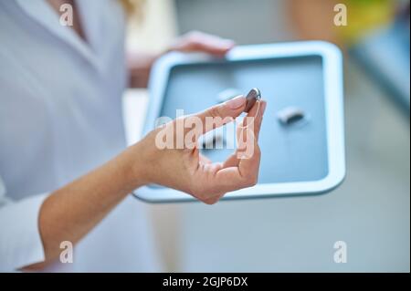 Mano femminile che mostra i migliori apparecchi acustici Foto Stock