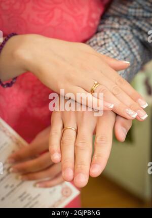 Le mani degli sposi novelli con gli anelli di cerimonia nuziale inoltre hanno certificato sul matrimonio Foto Stock