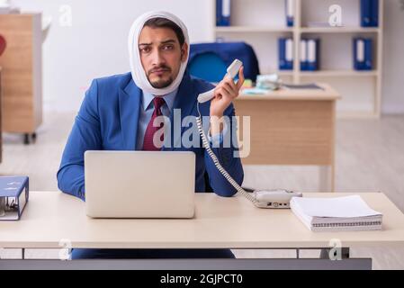 Giovane impiegato di uomini d'affari che soffre di mal di denti sul posto di lavoro Foto Stock