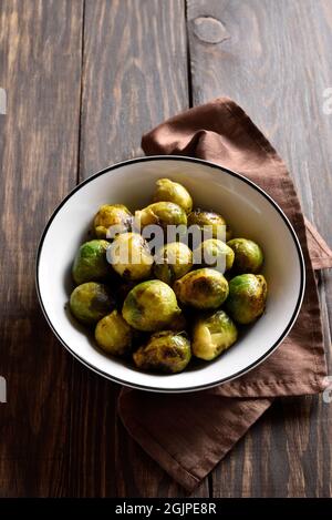 germogli di bruxelles arrostiti in ciotola su sfondo di legno con spazio di testo libero. Foto Stock