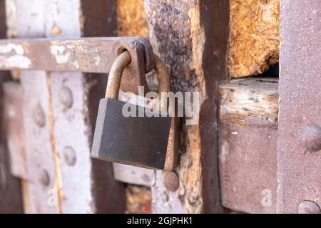 Sicurezza senza concetto di accesso. Lucchetto in metallo arrugginito bloccato su asta di acciaio proibito, anche se è vecchio, l'ingresso nell'edificio. Vintage intemperato danneggiato cl Foto Stock