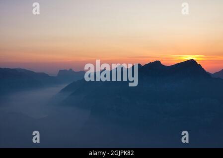 Tramonti sulle cime montane svizzere al tramonto con valle e lago, paesaggio colorato Foto Stock