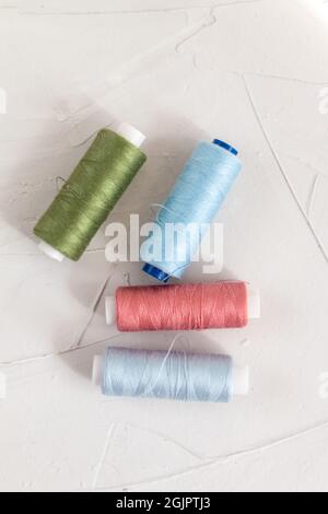 Filo di cotone colorato su sfondo grigio, moda lenta e concetto di cucito per la casa Foto Stock