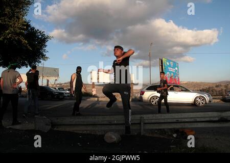 Cisgiordania, Nablus, Palestina. 11 Settembre 2021. Un palestinese mascherato gettando pietre durante la manifestazione. I dimostranti palestinesi dimostrano solidarietà con i prigionieri palestinesi detenuti nelle carceri israeliane vicino al checkpoint di Hawara, a sud di Nablus in Cisgiordania, e ci sono circa 5,000 prigionieri nelle carceri israeliane. Credit: Nasser Ishtayeh/ZUMA Wire/Alamy Live News Foto Stock