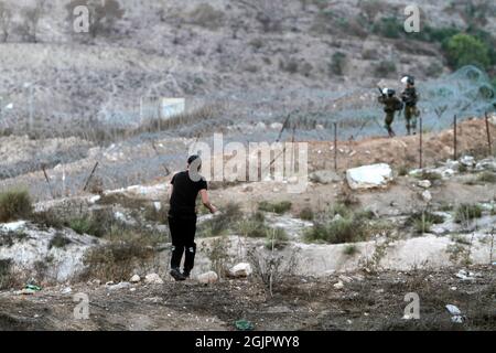 Cisgiordania, Nablus, Palestina. 11 Settembre 2021. Un palestinese mascherato gettando pietre durante la manifestazione. I dimostranti palestinesi dimostrano solidarietà con i prigionieri palestinesi detenuti nelle carceri israeliane vicino al checkpoint di Hawara, a sud di Nablus in Cisgiordania, e ci sono circa 5,000 prigionieri nelle carceri israeliane. Credit: Nasser Ishtayeh/ZUMA Wire/Alamy Live News Foto Stock