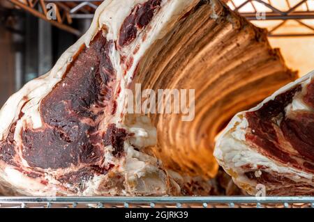 Bistecca di manzo in armadietto stagionato di carne secco. Bistecca alla griglia sul frigorifero nel delizioso ristorante gourmet. Carne secca che invecchia in deposito freddo. Taglio stagionato a secco Foto Stock