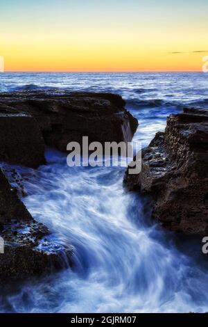 Rocce di sabbia screpolate sulla spiaggia di Narrabeen della costa del Pacifico di Sydney con onde panoramiche all'alba - mare delle spiagge del Nord. Foto Stock