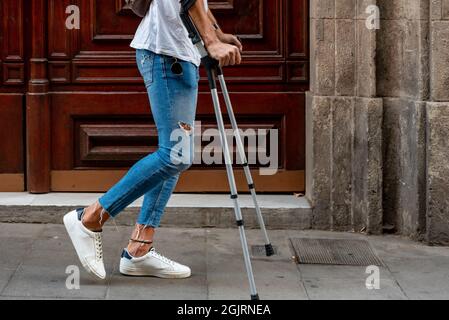 Giovane irriconoscibile con stampelle che visitano la città Foto Stock