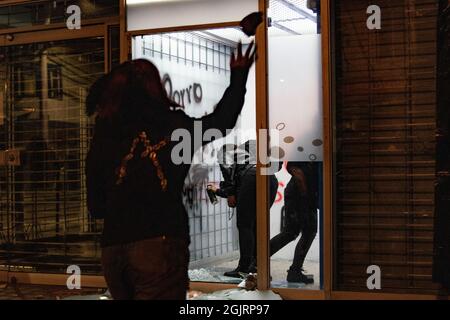 Un dimostratore lancia rocce e debree come altri vandalizza un bancomat alla stazione di polizia di Villa Luz CAI erano agenti di polizia torturati Javier Ordoñez il 9 settembre 2020, più tardi lo stesso giorno diverse stazioni di polizia sono stati vandalizzati e bruciati a causa della morte di Ordoñez, e lasciando un bilancio di morte di 12 altre persone che sono morte per uso di armi da fuoco della polizia e casi di brutalità la stessa notte. Il 9 settembre 2021 a Bogotà, Colombia. Foto Stock