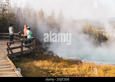 Wyoming, USA - 25 agosto 2021: I turisti scattano foto di una sorgente termale calda con vapore nella zona di Norris Geyser Basin Foto Stock