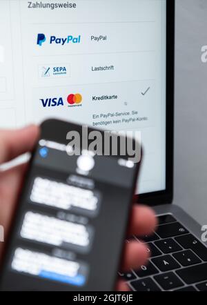 Rottweil, Germania. 9 settembre 2021. Un uomo tiene il suo smartphone per l'autenticazione a due fattori, mentre lo schermo di un laptop visualizza vari metodi di pagamento. Credit: Silas Stein/dpa/Alamy Live News Foto Stock