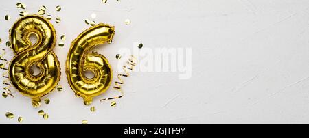 palloncino dorato numero ottantasei. Tessera di compleanno o anniversario con l'iscrizione 86. Sfondo grigio in cemento. Celebrazione dell'anniversario. Banner Foto Stock