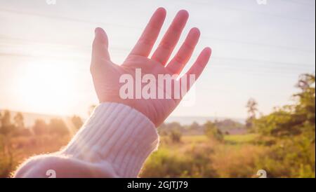 Messa a fuoco morbida mano donna che raggiunge la natura e il cielo Foto Stock