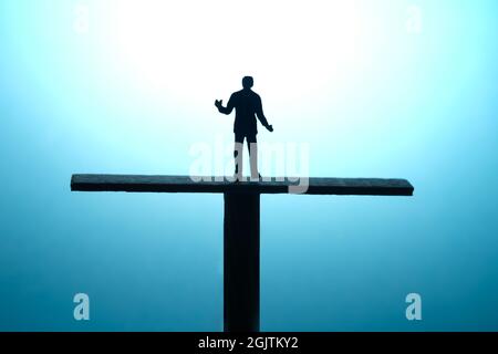 Fotografia di personaggi giocattolo in miniatura. Concetto di scelta aziendale. Un silhouette di uomo d'affari che si è arrugato si levano in piedi sopra l'equilibrio della bilancia. Foto immagine Foto Stock