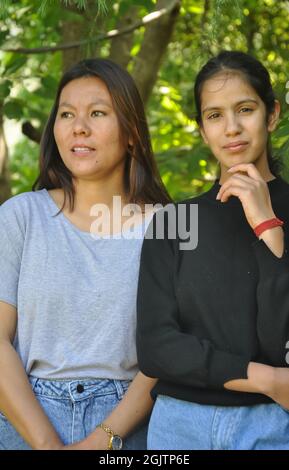 Ritratto di due belle ragazze del sud asiatico in posa all'aperto contro l'albero lesfy con guardare la macchina fotografica Foto Stock