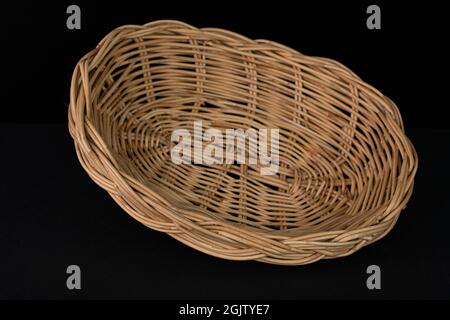 Un bel cestino di rattan su sfondo nero. Foto Stock