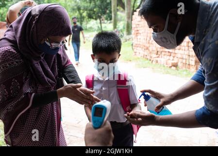 Dhaka, Dhaka, Bangladesh. 12 settembre 2021. Un funzionario controlla la temperatura corporea di uno studente al suo arrivo alla scuola di Dhaka. Il governo del Bangladesh ha revocato le restrizioni alle istituzioni educative dopo 18 mesi di arresti a causa della pandemia del coronavirus Covid-19. (Credit Image: © Fatima-Tuj Johora/ZUMA Press Wire) Foto Stock