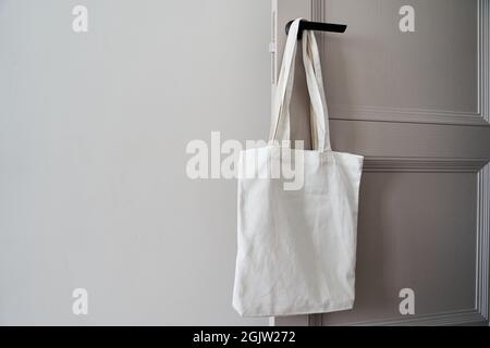 Borsa bianca ecologica appesa alla maniglia della portiera. Borsa tote in tela Foto Stock