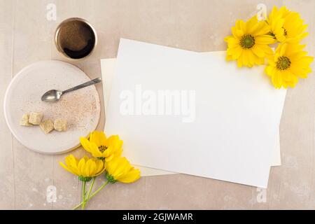 Mockup vuoto bianco di nozze o biglietti d'auguri su sfondo rosa tavolo vintage, banner web per design con grandi fiori gialli, tazza di caffè, piatto con Foto Stock