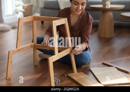 Focalizzato indiano donna uso semplice strumenti raccogliere auto assemblaggio mobili Foto Stock