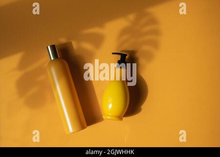 Mockup di bottiglie cosmetiche gialle con foglie di monstera ombra su sfondo giallo. Un'immagine creativa e minimalista di un prodotto cosmetico. Il concetto o Foto Stock