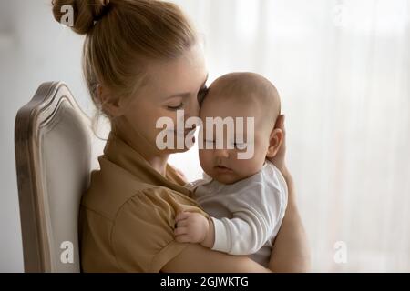 Felice mamma tranquilla abbracciare e baciare adorabile bambino Foto Stock