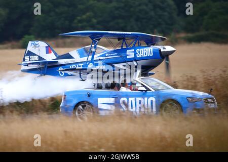 Rich Goodwin volare il suo blu Pitts Special biplanare G-JPIT accanto a un'auto sportiva Audi all'Abingdon Air & Country Show 2021 Foto Stock