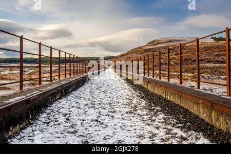 Un vecchio viadotto ferroviario coperto di neve presso la Big Water of Fleet presso la Cairnsmore of Fleet National Nature Reserve, Dumfries e Galloway, Scozia Foto Stock