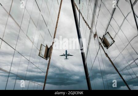 Aereo. L'aereo vola su alti edifici moderni sullo sfondo di un cielo blu scuro con nuvole e nuvole. Foto Stock