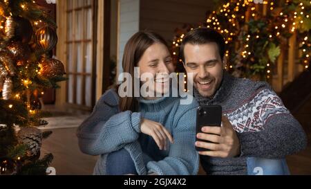 Sorridente giovane coppia europea positiva che guarda lo schermo dello smartphone. Foto Stock