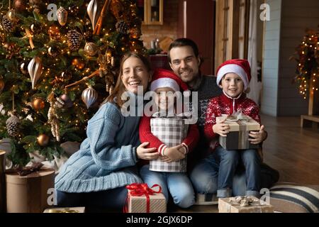 Ritratto di famiglia felice emotivo seduto vicino all'albero di Natale decorato. Foto Stock