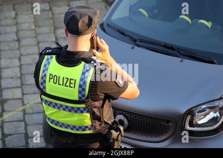 Amburgo, Germania. 9 settembre 2021. Un poliziotto parla al telefono durante un importante controllo sul mercato del pesce di Amburgo. La polizia di Amburgo, con il supporto di agenti di polizia specializzati provenienti da dieci stati federali, Austria e Svizzera, nonché il supporto delle dogane, ha controllato numerose persone e veicoli nel corso della quindicesima settimana del dis (Drug Detection in Road Traffic). Credit: Bodo Marks/dpa/Bodo Marks/dpa/Alamy Live News Foto Stock