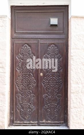 Vecchia porta in legno intemperie con ornamenti intagliati Foto Stock