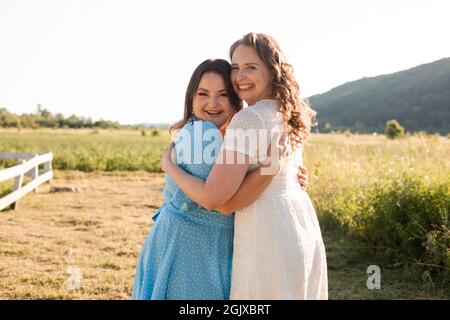 Due sorelle si abbracciano all'azienda Foto Stock