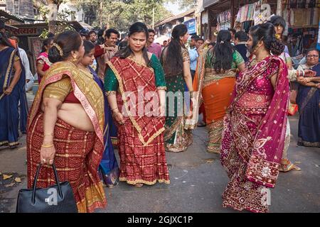 Una festa di nozze a Mumbai, India, che si spillano fuori nella strada, con due ospiti femminili che si guardano l'un l'altro in quello che sembra essere un modo ostile Foto Stock
