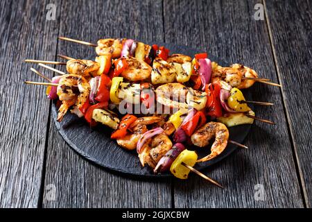 Gamberi Kabobs alla griglia con cipolla rossa, pepe dolce e ananas su un piatto di pietra nera Foto Stock