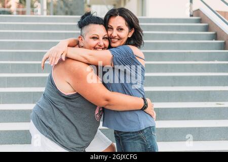 Due sorelle gemelle adulte abbracciano. Stili diversi Foto Stock