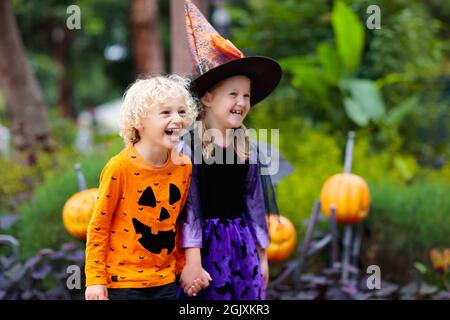 Bambino in costume di Halloween. Trucchi o delizia per i bambini. Ragazzino e ragazza vestita come strega con cappello che tiene lanterna di zucca e secchio di caramelle. Famiglia Foto Stock