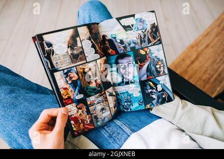 L'uomo legge il fumetto nel soggiorno di casa. Foto Stock